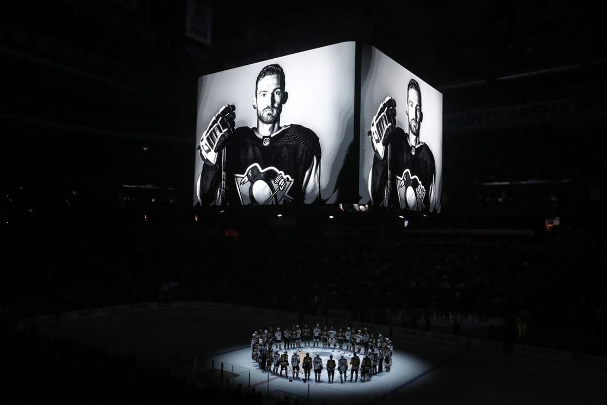 Oct 30, 2023; Pittsburgh, Pennsylvania, USA;  Members of the Anaheim Ducks and the Pittsburgh Penguins stand at center ice for a moment of silence at the PPG Paints Arena to honor former Penguin forward Adam Johnson (on scoreboard) who was tragically killed in a hockey related accident in Europe.