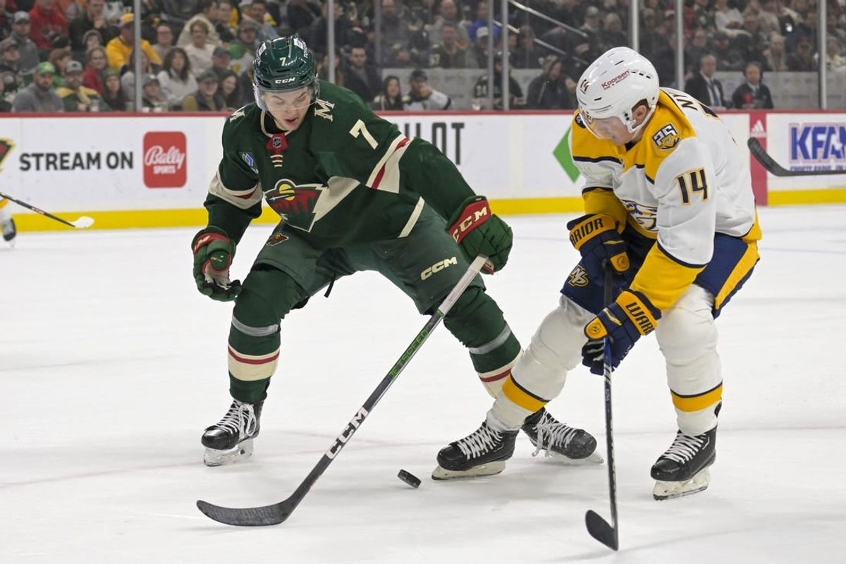 Jan 25, 2024; Saint Paul, Minnesota, USA; Minnesota Wild defenseman Brock Faber (7) poke-checks the puck away from Nashville Predators forward Gustav Nyquist (14) during the first period at Xcel Energy Center.