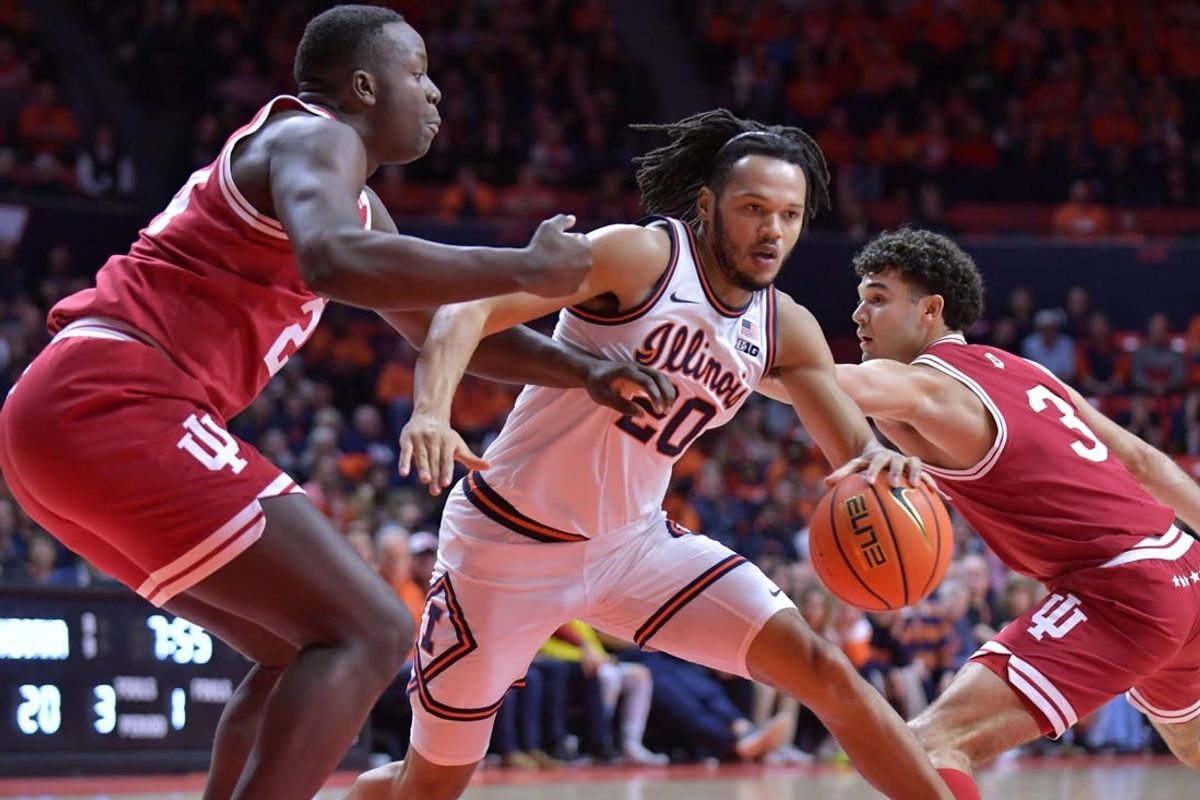 Jan 27, 2024; Champaign, Illinois, USA;  Illinois Fighting Illini forward Ty Rodgers (20) drives the ball between Indiana Hoosiers forward Payton Sparks (24) and guard Anthony Leal (3) during the first half at State Farm Center.