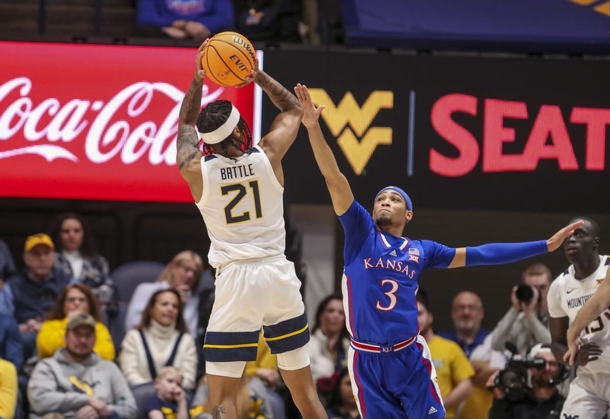 Jan 20, 2024; Morgantown, West Virginia, USA; West Virginia Mountaineers guard RaeQuan Battle (21) shoots over Kansas Jayhawks guard Dajuan Harris Jr. (3) during the first half at WVU Coliseum.