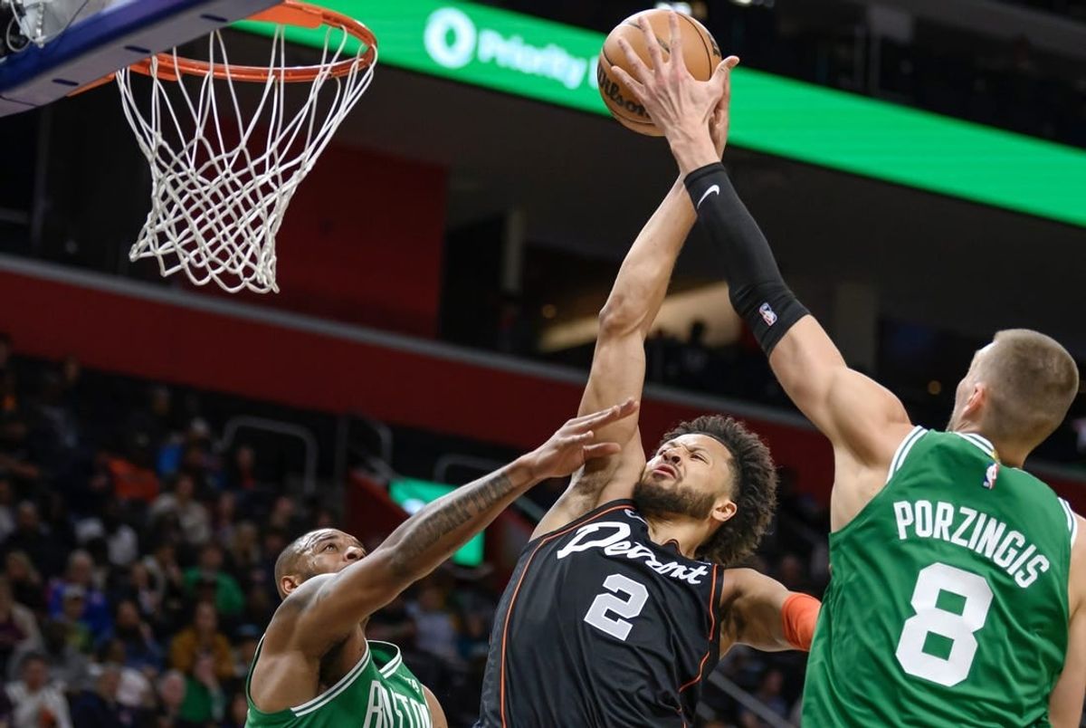 Mar 22, 2024; Detroit, Michigan, USA; Detroit Pistons guard Cade Cunningham (2) gets fouled while driving to the basket against  Boston Celtics forward Xavier Tillman (26) and  center Kristaps Porzingis (8) in the first quarter at Little Caesars Arena.