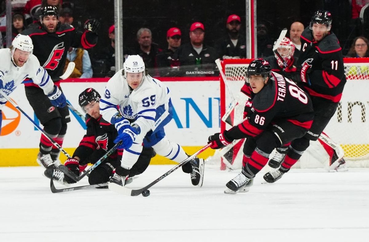 Mar 24, 2024; Raleigh, North Carolina, USA;  Carolina Hurricanes defenseman Brett Pesce (22) and left wing Teuvo Teravainen (86) battle Toronto Maple Leafs left wing Tyler Bertuzzi (59) for the puck during the first period at PNC Arena.