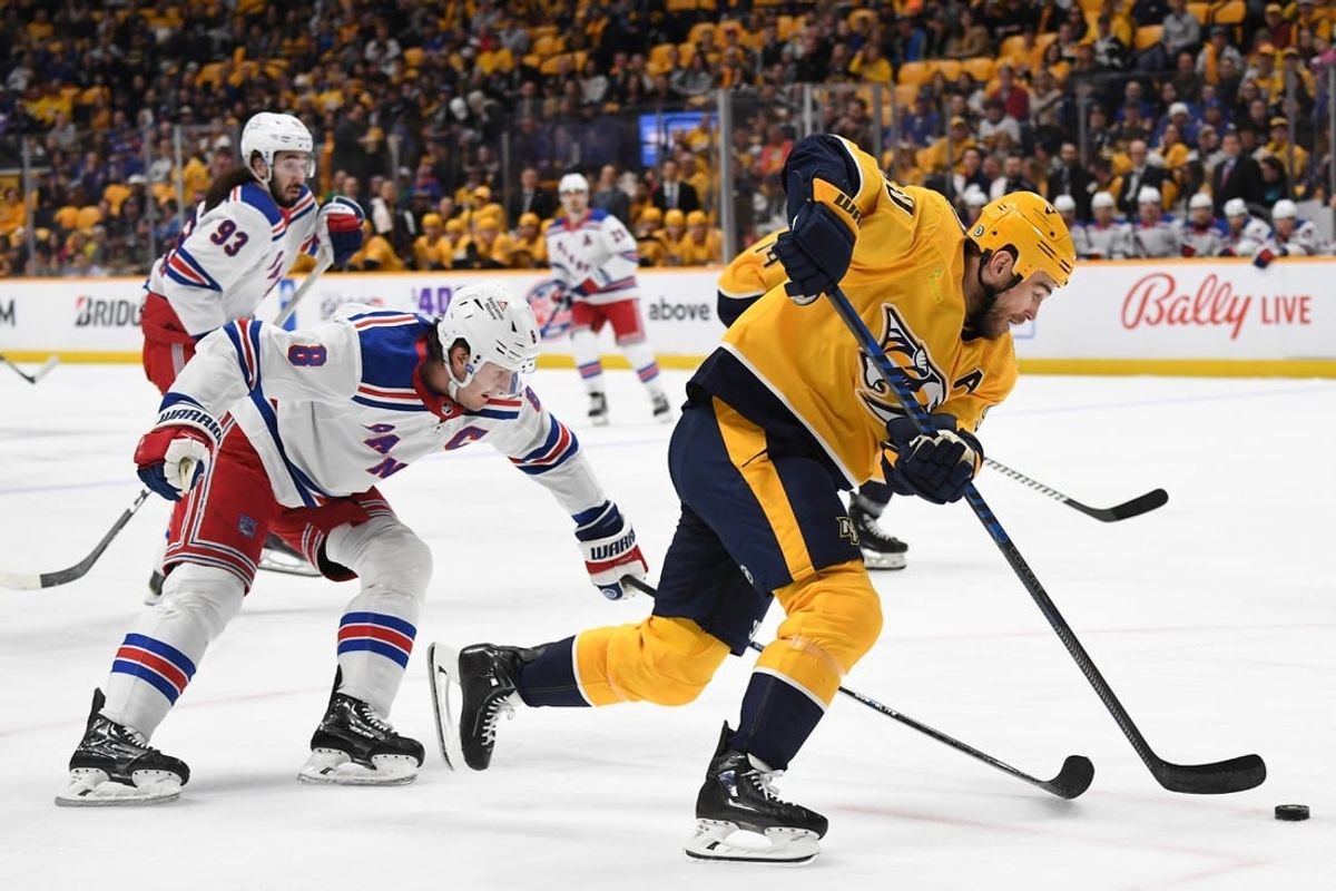 Dec 2, 2023; Nashville, Tennessee, USA; Nashville Predators center Ryan O'Reilly (90) handles the puck against New York Rangers defenseman Jacob Trouba (8) during the first period at Bridgestone Arena.