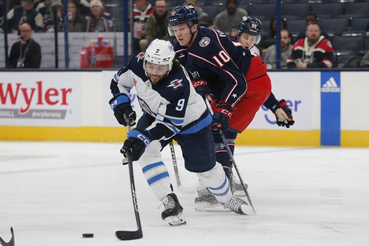 Mar 17, 2024; Columbus, Ohio, USA; Winnipeg Jets left wing Alex Iafallo (9) passes the puck as Columbus Blue Jackets left wing Dmitri Voronkov (10) trails the play during the first period at Nationwide Arena.
