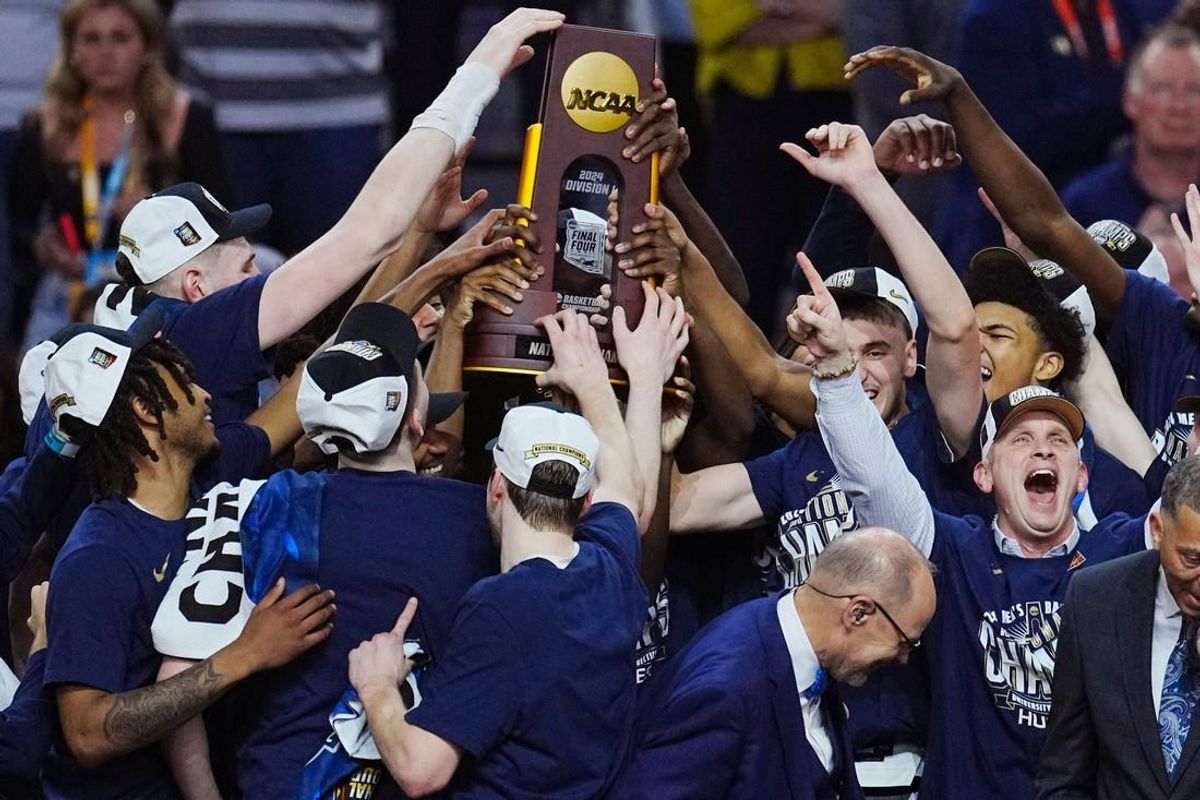 Connecticut Huskies head coach Dan Hurley and players celebrate with the trophy after defeating the Purdue Boilermakers in the national championship game of the Final Four of the 2024 NCAA Tournament at State Farm Stadium in Glendale on April 8, 2024.