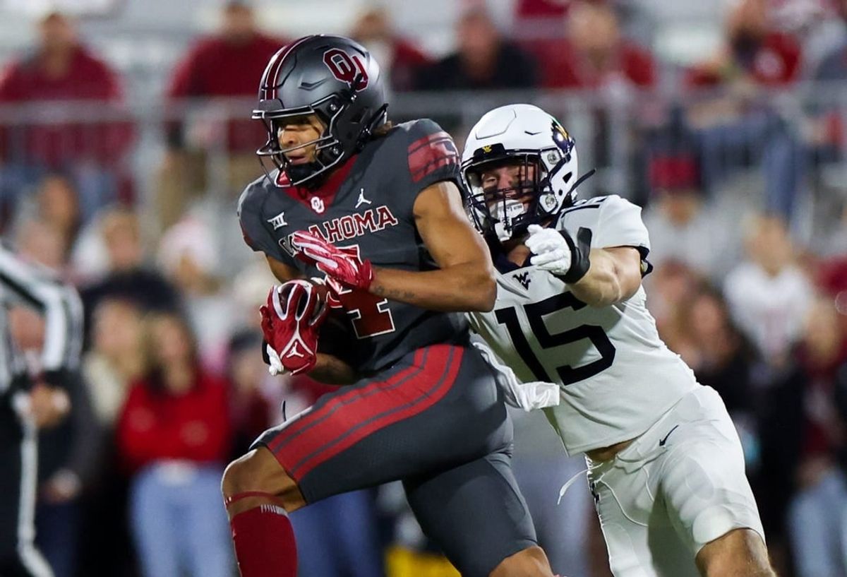 Nov 11, 2023; Norman, Oklahoma, USA;  Oklahoma Sooners wide receiver Nic Anderson (4) runs with the ball as West Virginia Mountaineers linebacker Ben Cutter (15) defends during the first quarter at Gaylord Family-Oklahoma Memorial Stadium.