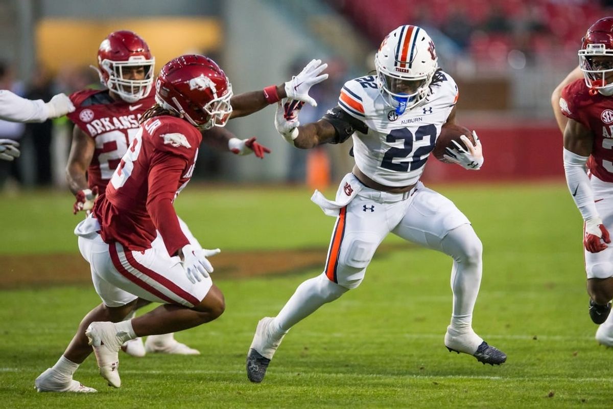 Nov 11, 2023; Fayetteville, Arkansas, USA;  Auburn Tigers running back Damari Alston (22) tries to fight off Arkansas Razorbacks defensive back TJ Metcalf (18) during the third quarter at Donald W. Reynolds Razorback Stadium. Auburn won 48-10.