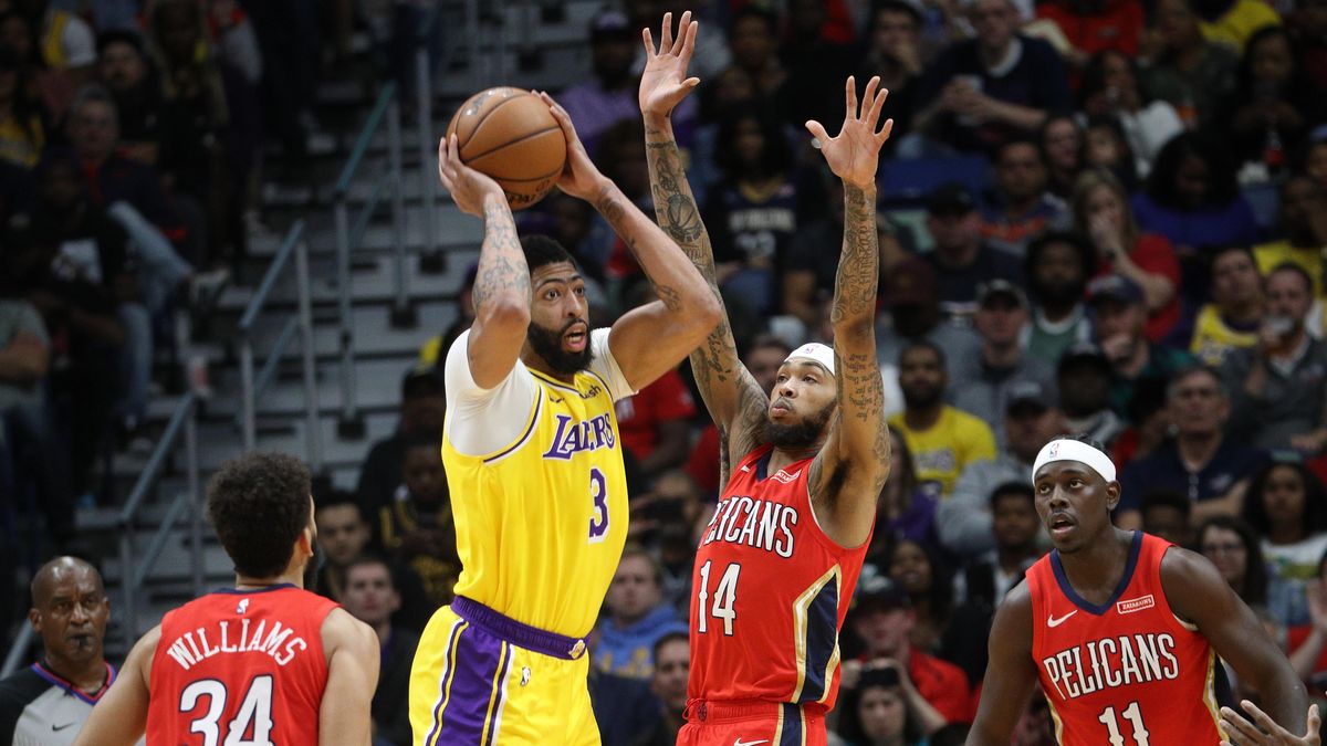 Anthony Davis passes the ball around Brandon Ingram at Smoothie King Center in New Orleans, Louisiana.