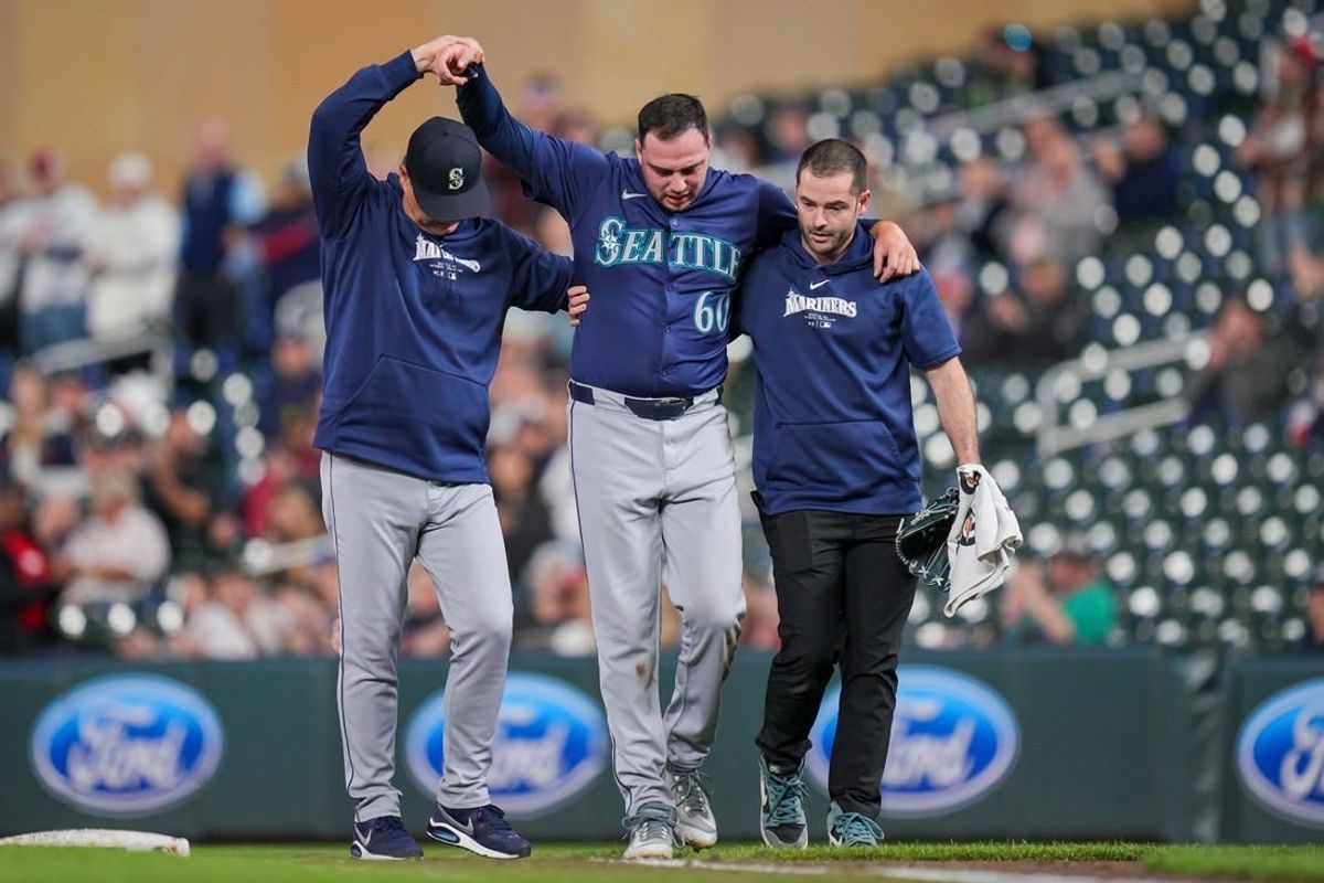 May 7, 2024; Minneapolis, Minnesota, USA; Seattle Mariners pitcher Tayler Saucedo (60) is helped off the field against the Minnesota Twins in the eighth inning at Target Field.