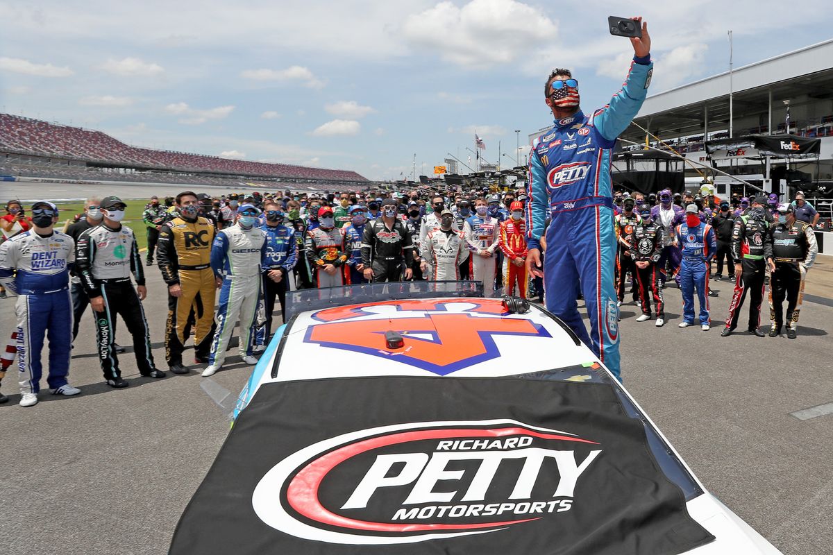 Bubba Wallace takes a selfie with  NASCAR drivers standing  behind in support prior to start of Geico 500 at Talladega on Monday.