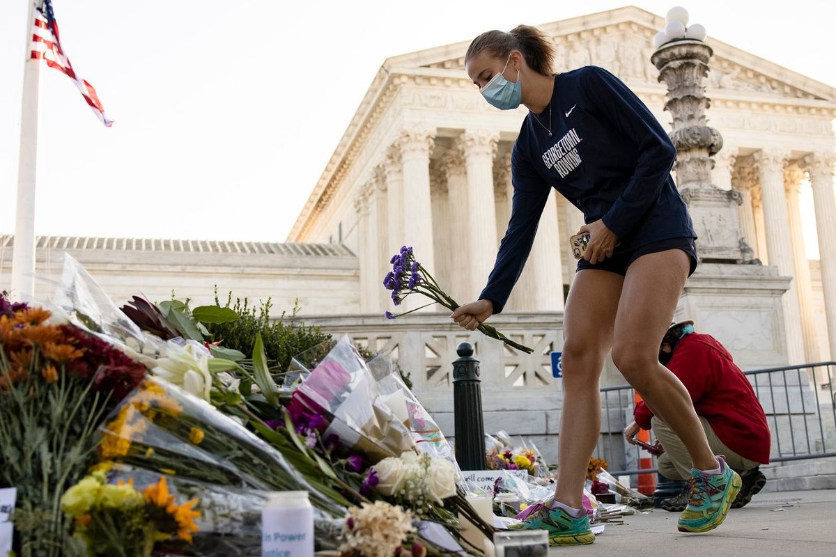 A member of the Georgetown  University Women’s Rowing Team places flowers at a makeshift memorial in  honor of Supreme Court Justice Ruth Bader Ginsburg in front of the U.S . Supreme Court on Saturday.