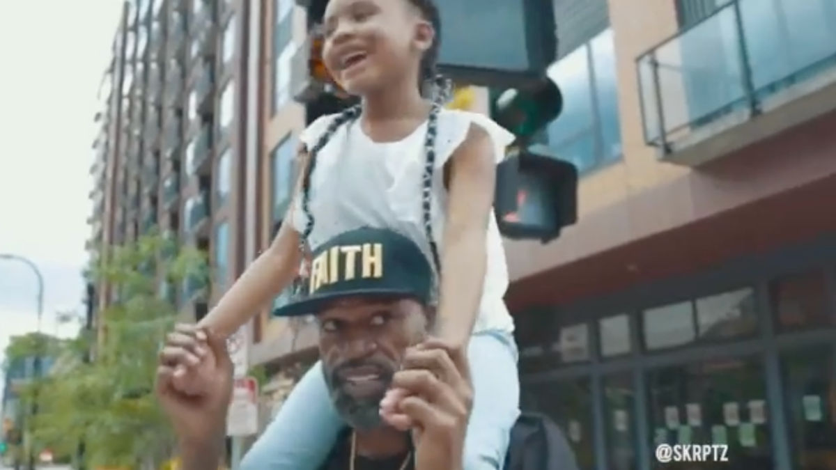 Stephen Jackson hodls the daughter of his “twin,” George Floyd, on his shoulders.