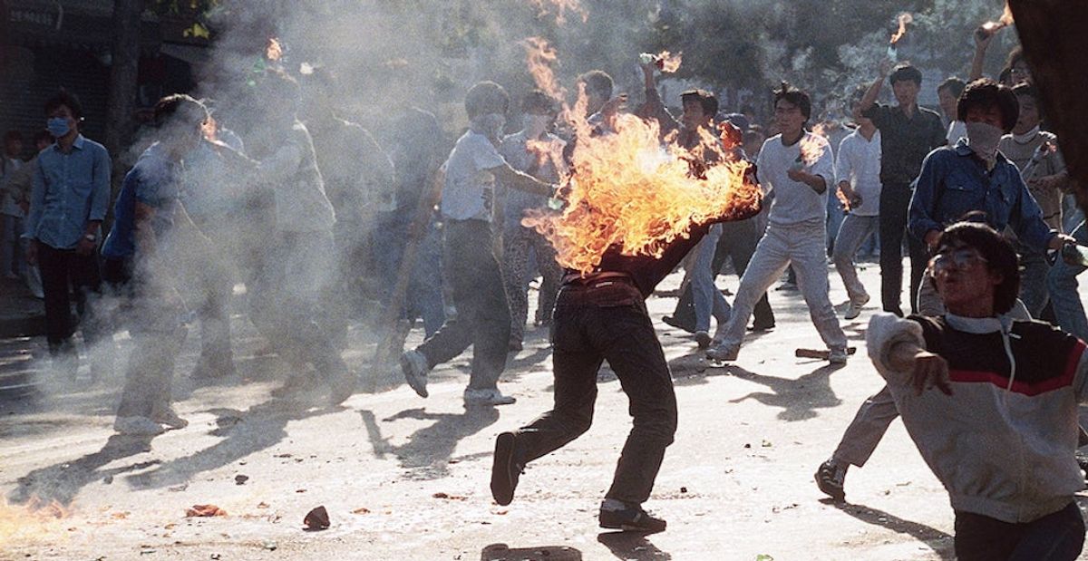 A South Korean student engulfed in flames runs for safety as his compatriots launch home-made firebombs toward riot police during anti-government, anti-Olympic demonstrations at Korea University in Seoul, South Korea on Sept. 29, 1988. (Photo credit:  [object Object] )