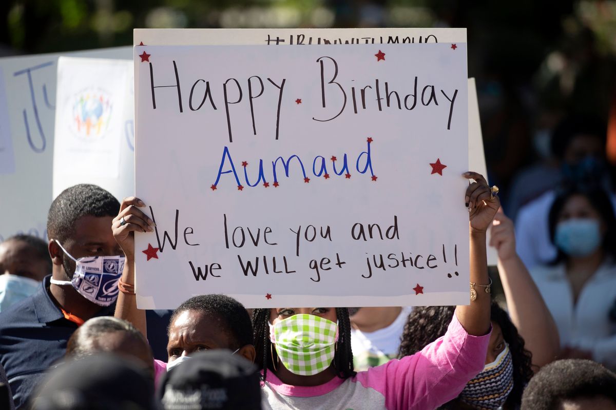 Woman holds up a sign wishing Ahmaud Arbery happy birthday at a protest in Brunswick, Ga.