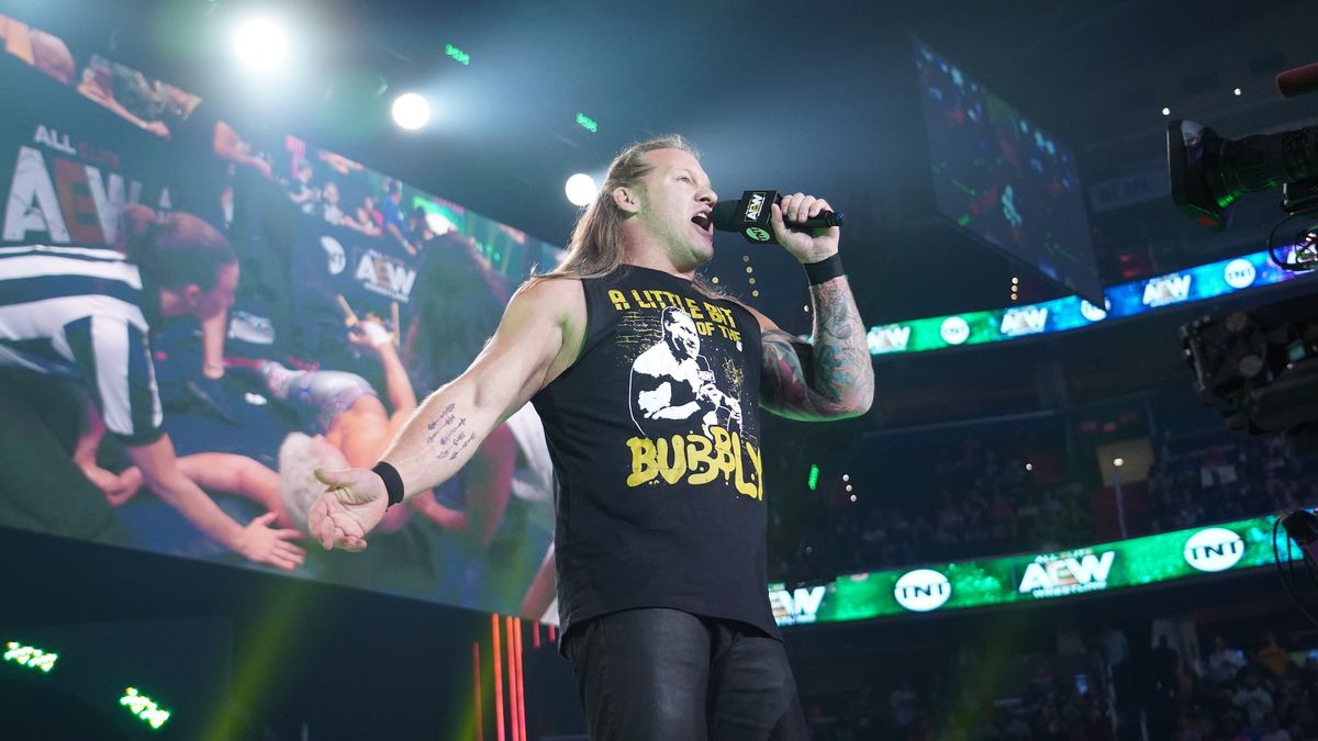 AEW World Heavyweight Champion Chris Jericho gloats after laying out Cody Rhodes, who can be seen on the big screen being tended to by referee Aubrey Edwards.