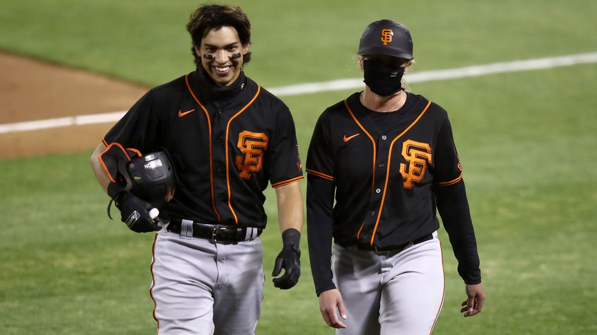Mauricio Dubon and first base coach Alyssa Nakken walk back to the dugout after the seventh inning of the Giants’ exhibition game against the Oakland As on Monday night.