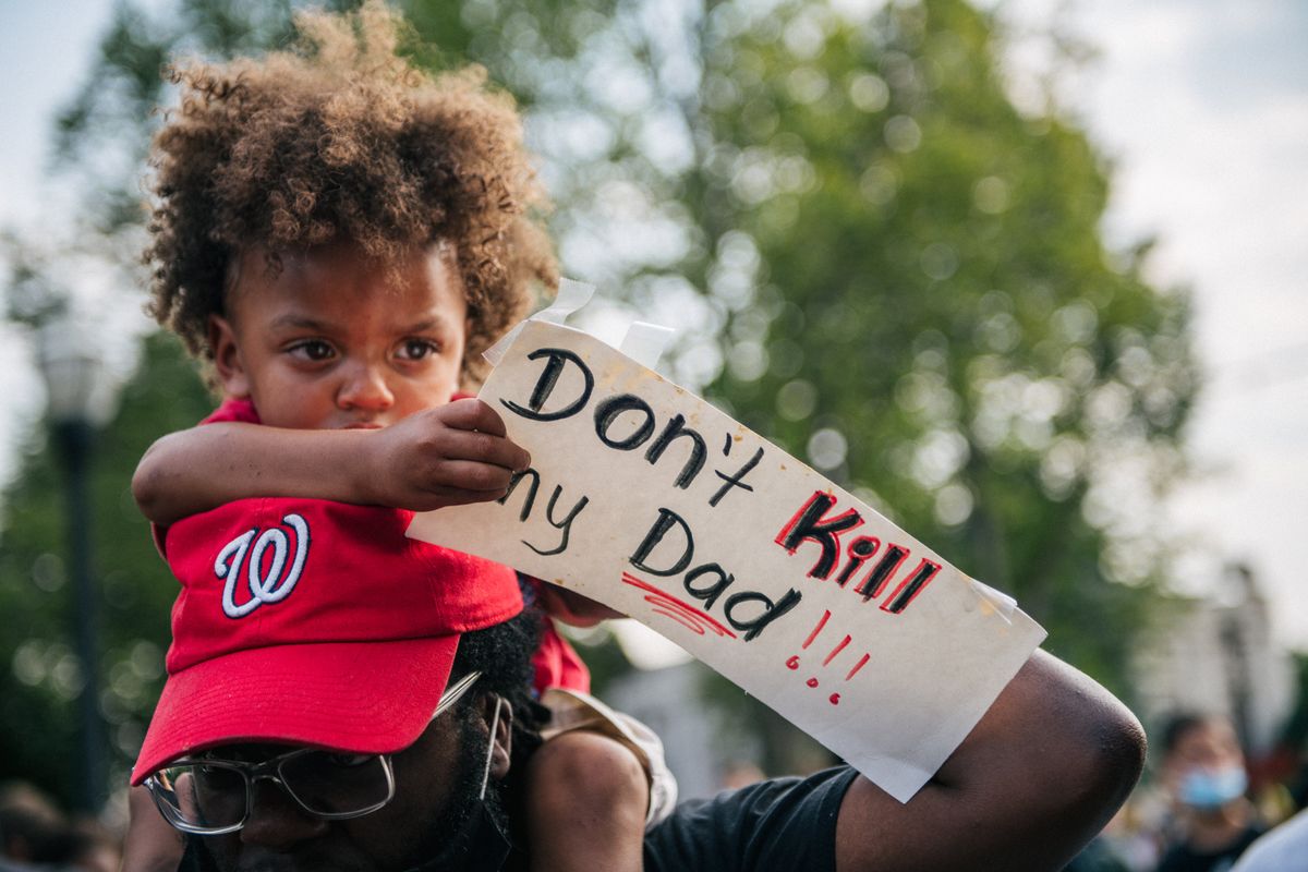 A child sits on his farther’s shoulders at a protest over the police shooting of Jacob Blake in Kenosha, Wis.