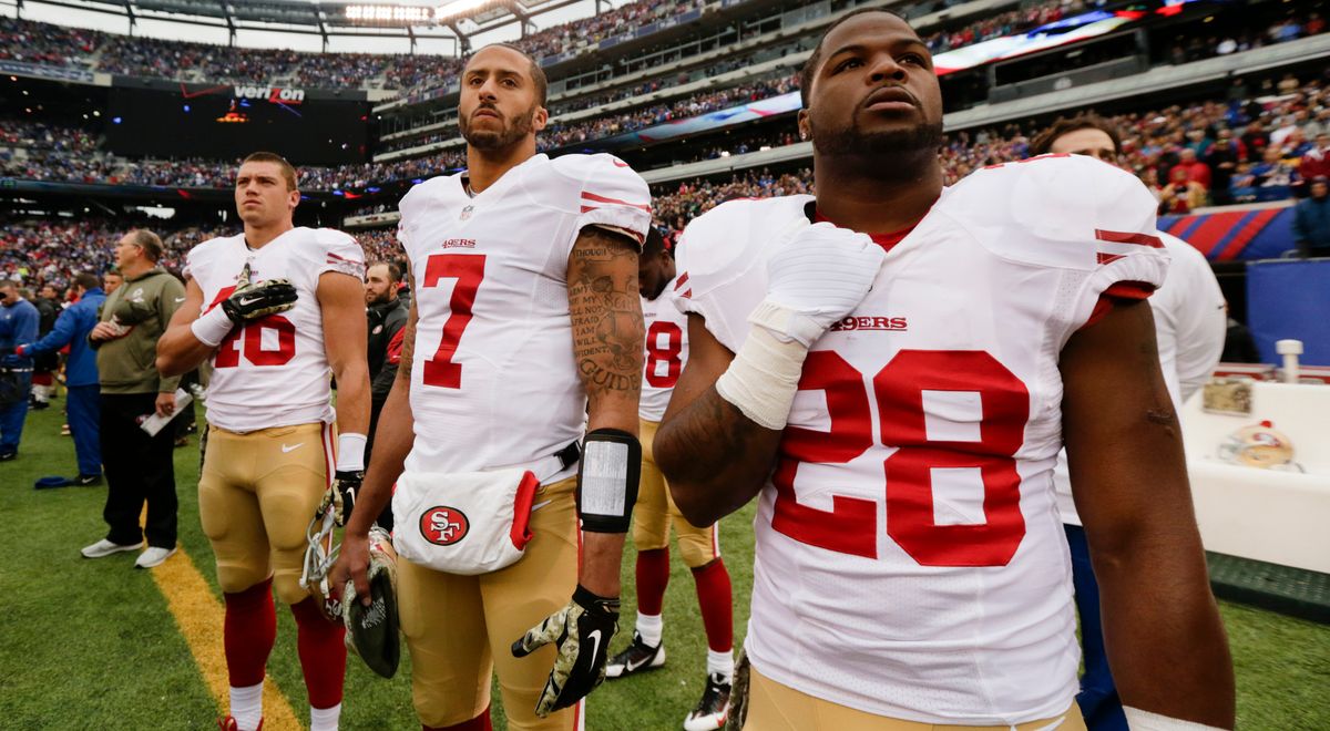 Colin Kaepernick and 49ers teammates stand during the national anthem in 2014. Photo credit: Julio Cortez/ [object Object]