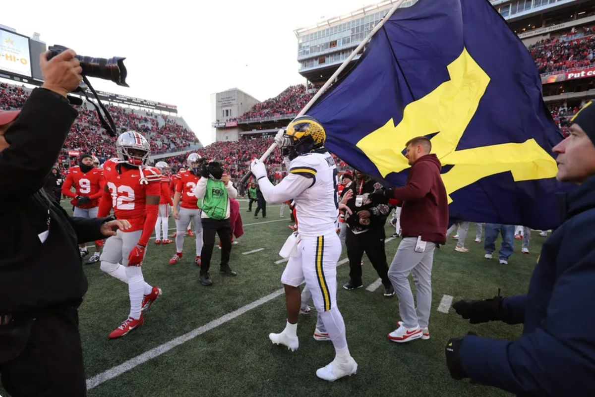 30 de novembro de 2024; Columbus, Ohio, EUA; O ponta defensiva do Michigan Wolverines, Derrick Moore (8), tenta fincar a bandeira no logotipo do Ohio State Buckeyes enquanto o ponta defensiva do Ohio State Buckeyes, Jack Sawyer (33), rasga a bandeira após o jogo no Ohio Stadium. Crédito obrigatório: Joseph Maiorana-Imagn Images