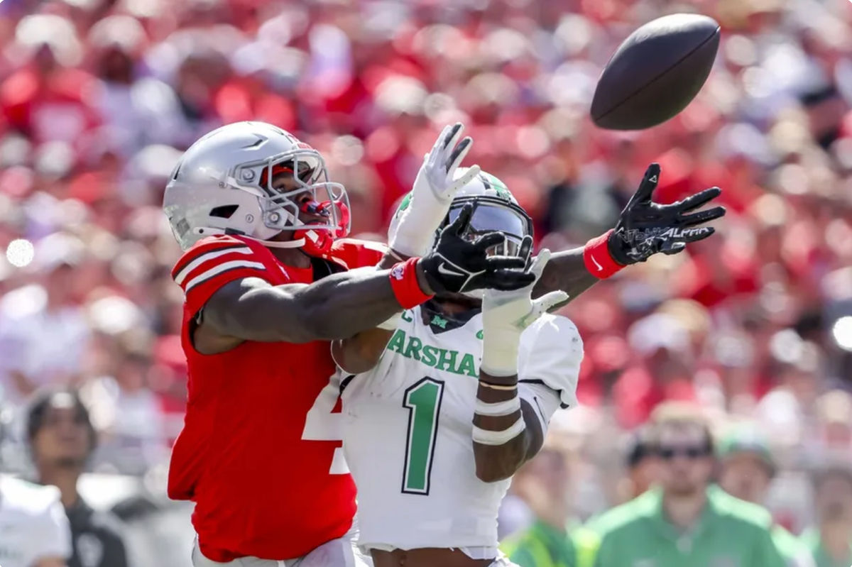 21 de setembro de 2024; Columbus, Ohio, EUA; O wide receiver do Ohio State Buckeyes, Jeremiah Smith (4), vai para a bola com o defensive back do Marshall Thundering Herd, Josh Moten (1), durante o primeiro quarto no Ohio Stadium. Crédito obrigatório: Joseph Maiorana-Imagn Images
