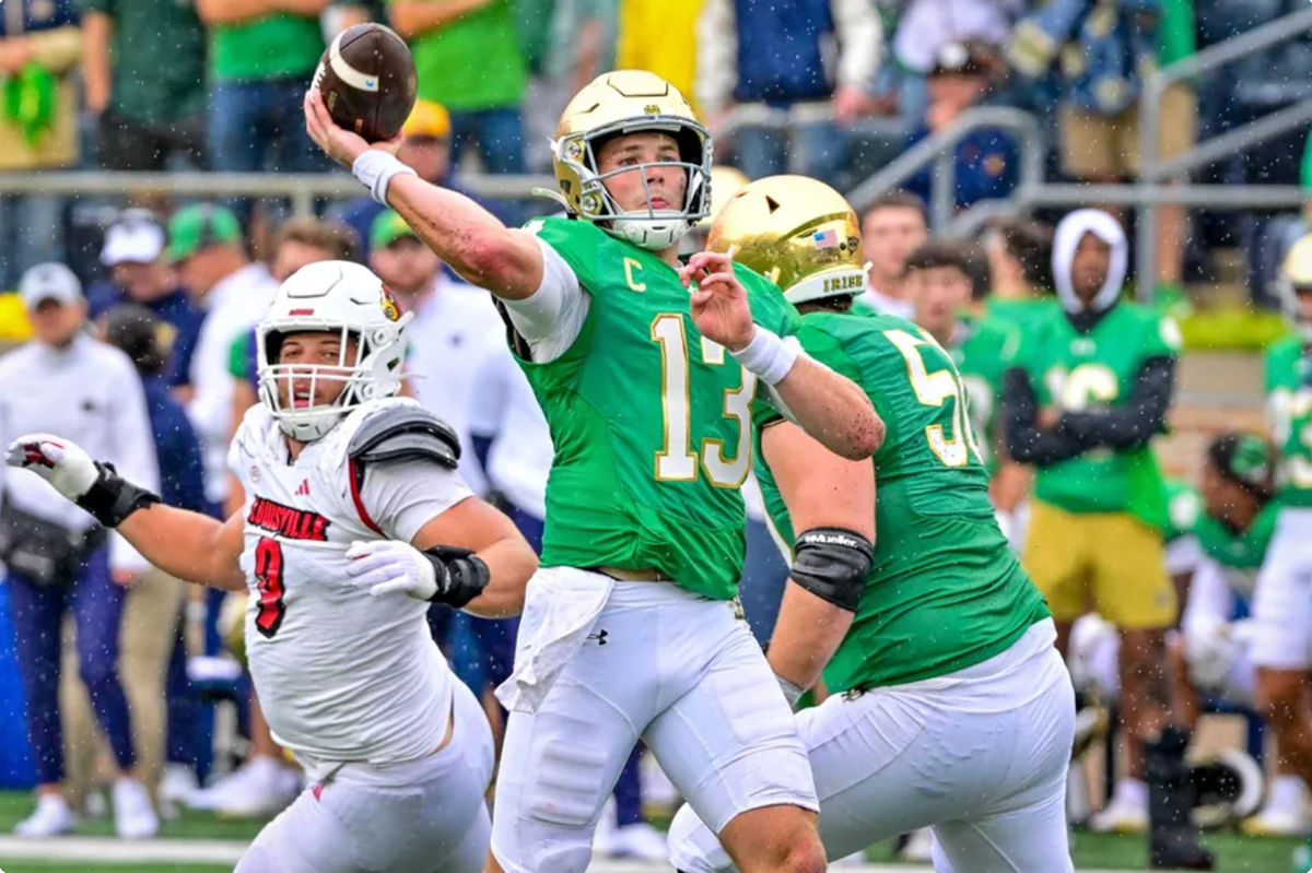 28 de setembro de 2024; South Bend, Indiana, EUA; O quarterback do Notre Dame Fighting Irish, Riley Leonard (13), lança um passe para touchdown contra o Louisville Cardinals no primeiro quarto no Notre Dame Stadium. Crédito obrigatório: Matt Cashore-Imagn Images