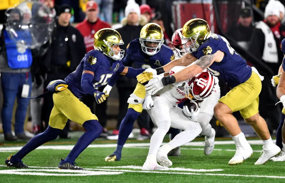 20 de dezembro de 2024; Notre Dame, Indiana, EUA; O jogador de linha defensiva do Notre Dame Fighting Irish Joshua Burnham (40) e o cornerback Leonard Moore (15) enfrentam o wide receiver do Indiana Hoosiers Myles Price (4) durante o terceiro quarto no Notre Dame Stadium. Crédito obrigatório: Matt Cashore-Imagn Images