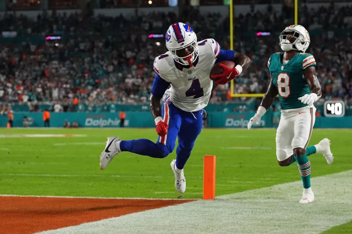 12 de septiembre de 2024; Miami Gardens, Florida, EE. UU.; El corredor de los Buffalo Bills, James Cook (4), se lanza para anotar un touchdown ante el safety de los Miami Dolphins, Jevon Holland (8), durante la primera mitad en el Hard Rock Stadium. Crédito obligatorio: Jasen Vinlove-Imagn Images