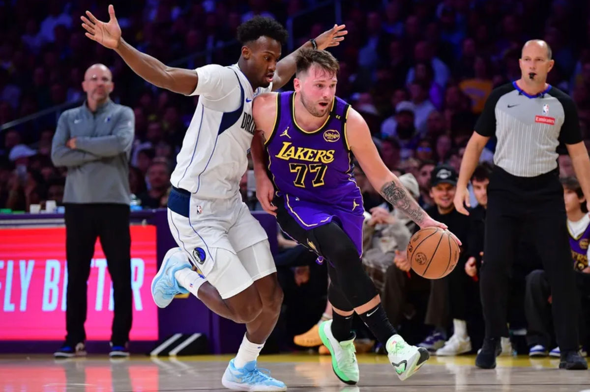 25 de fev de 2025; Los Angeles, Califórnia, EUA; O armador do Los Angeles Lakers, Luka Doncic (77), dribla a bola passando pelo atacante do Dallas Mavericks, Olivier-Maxence Prosper (8), durante o segundo tempo na Crypto.com Arena. Crédito obrigatório: Gary A. Vasquez-Imagn Images