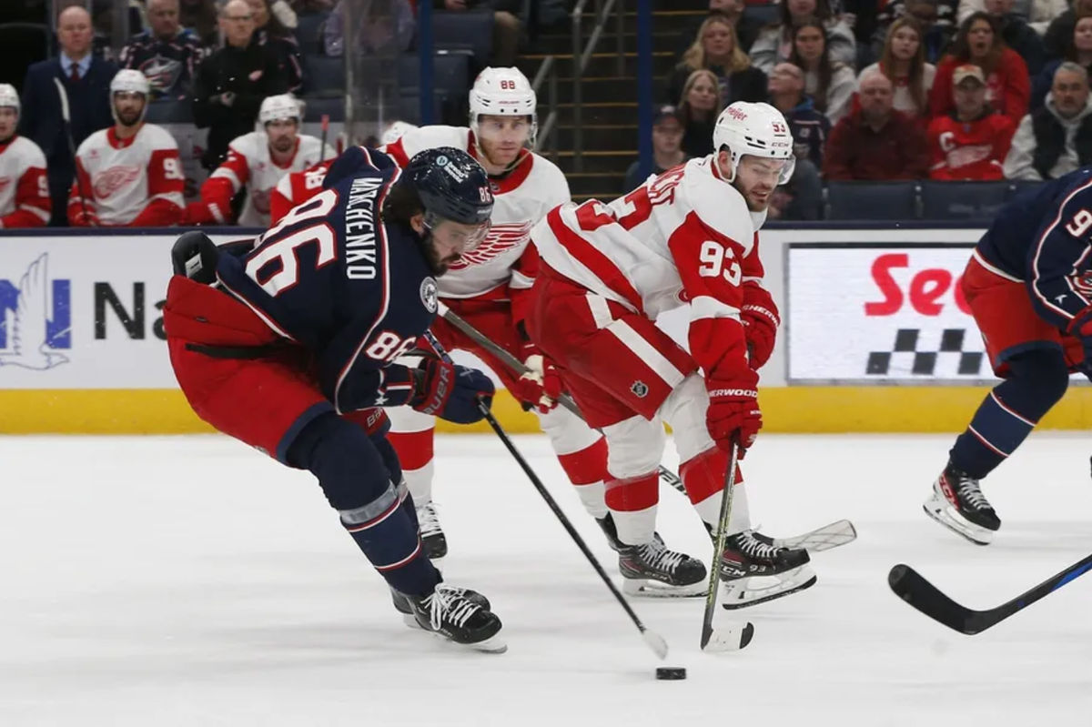 2 de janeiro de 2025; Columbus, Ohio, EUA; O ala direito do Columbus Blue Jackets, Kirill Marchenko (86), rouba o disco do ala direito do Detroit Red Wings, Alex DeBrincat (93), durante o segundo período na Nationwide Arena. Crédito obrigatório: Russell LaBounty-Imagn Images