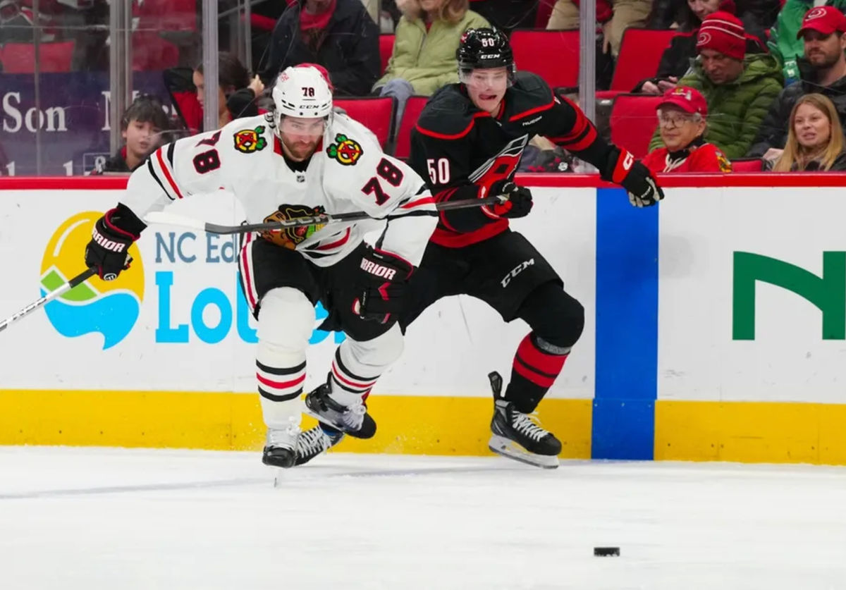 30 de janeiro de 2025; Raleigh, Carolina do Norte, EUA; O ala esquerdo do Carolina Hurricanes, Eric Robinson (50), e o defensor do Chicago Blackhawks, TJ Brodie (78), assistem ao disco durante o primeiro período no Lenovo Center. Crédito obrigatório: James Guillory-Imagn Images
