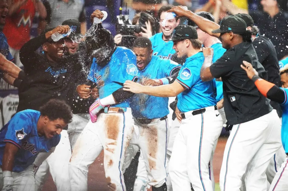 Mar 30, 2025; Miami, Florida, USA; Miami Marlins designated hitter Derek Hill, left, celebrates scoring the winning run on a wild pitch against the Pittsburgh Pirates in the ninth inning at loanDepot Park. Mandatory Credit: Jim Rassol-Imagn Images