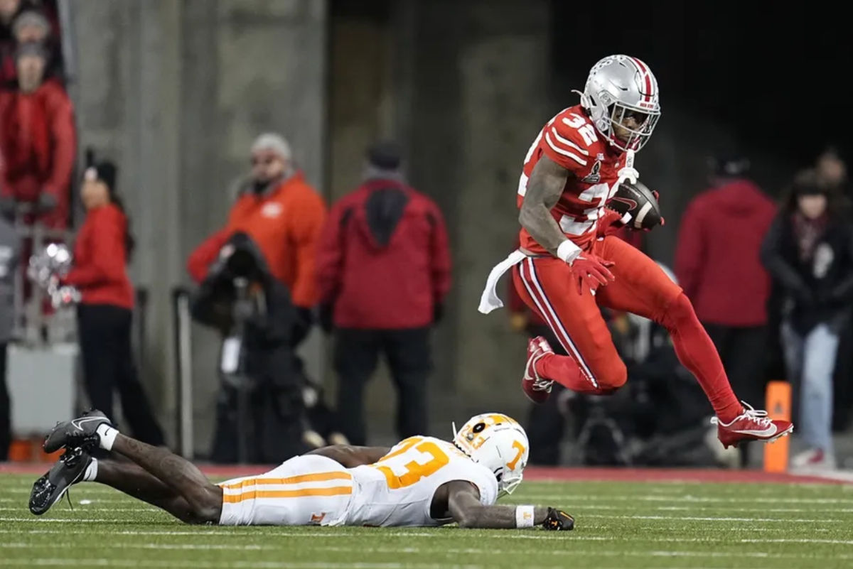 Dec 21, 2024; Columbus, Ohio, USA; Ohio State Buckeyes running back TreVeyon Henderson (32) hurdles Tennessee Volunteers quarterback Gaston Moore (13) during the first half of a College Football Playoff first round game at Ohio Stadium. Mandatory Credit: Adam Cairns-Imagn Images
