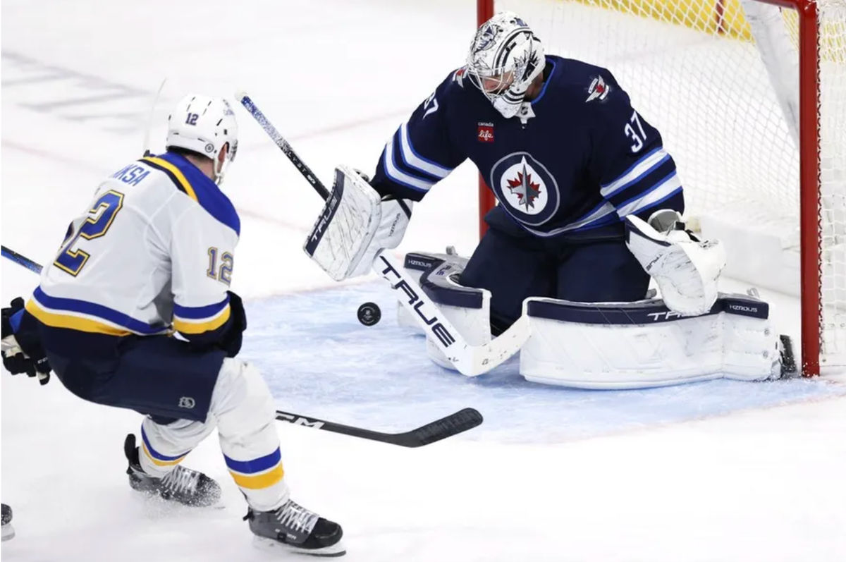 7 de abril de 2025; Winnipeg, Manitoba, CAN; O goleiro do Winnipeg Jets, Connor Hellebuyck (37), bloqueia um chute do pivô do St. Louis Blues, Radek Faksa (12), no terceiro período no Canada Life Centre. Crédito obrigatório: James Carey Lauder-Imagn Images