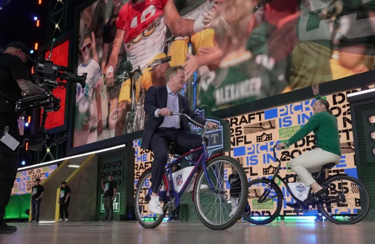 O comissário da NFL, Roger Goodell, e o ex-jogador do Packers, Clay Matthews, andam de bicicleta no palco antes do início da primeira rodada do Draft da NFL, quinta-feira, 24 de abril de 2025. FOTO: USA TODAY SPORTS IMAGES