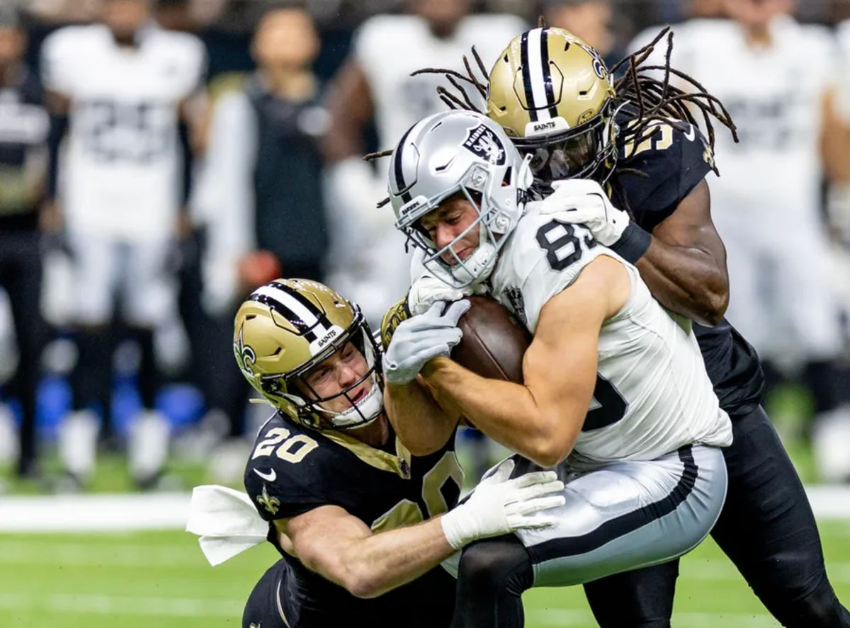 Dec 29, 2024; New Orleans, Louisiana, USA; New Orleans Saints linebacker Pete Werner (20) and linebacker Demario Davis (56) tackle Las Vegas Raiders tight end Brock Bowers (89) during the first half at Caesars Superdome. Mandatory Credit: Stephen Lew-Imagn Images