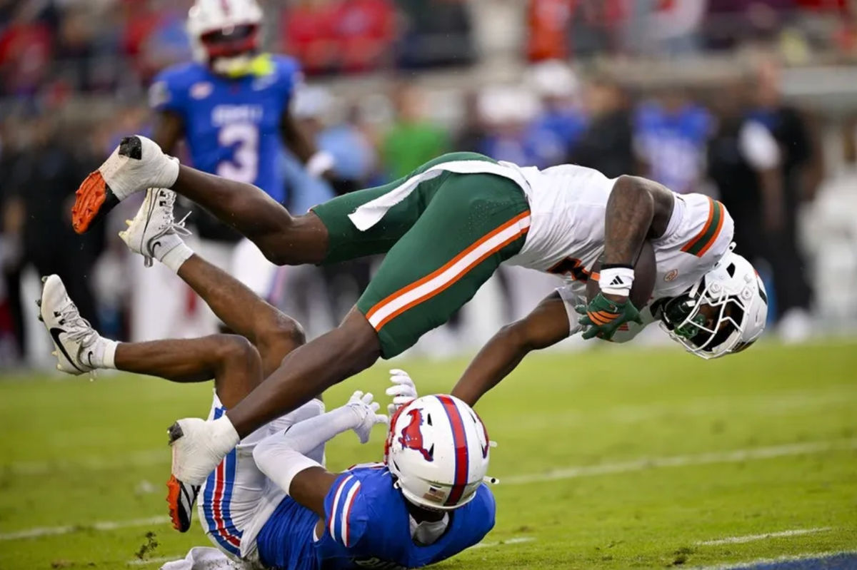 Nov 1, 2025; Dallas, Texas, USA; Miami Hurricanes wide receiver Joshisa Trader (1) dives over SMU Mustangs cornerback Marcellus Barnes Jr. (8) for a touchdown during the first quarter at Gerald J. Ford Stadium. Mandatory Credit: Jerome Miron-Imagn Images