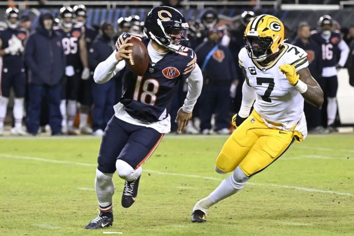 10 de enero de 2026; Chicago, Illinois, EE. UU.; El mariscal de campo de los Chicago Bears, Caleb Williams (18), se desliza mientras el linebacker de los Green Bay Packers, Quay Walker (7), aplica presión durante la primera mitad de un partido de la Ronda de Comodines de la NFC en el Soldier Field. Crédito obligatorio: Matt Marton-Imagn Images