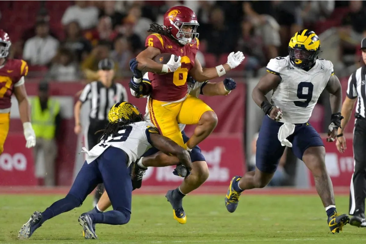 11 de outubro de 2025; Los Angeles, Califórnia, EUA; O wide receiver do USC Trojans, Makai Lemon (6), corre para uma primeira descida antes de ser parado pelo linebacker do Michigan Wolverines, Jimmy Rolder (30), pelo defensive back Rod Moore (19) e pelo defensive end Cameron Brandt (9) no segundo tempo no United Airlines Field, no Los Angeles Memorial Coliseum. Crédito obrigatório: Jayne Kamin-Oncea-Imagn Images