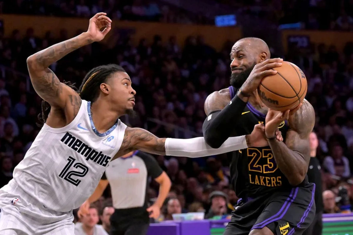 2 de enero de 2026; Los Ángeles, California, EE. UU.; El base de los Memphis Grizzlies, Ja Morant (12), defiende al alero de Los Angeles Lakers, LeBron James (23), mientras este penetra hacia la canasta durante la primera mitad en el Crypto.com Arena. Crédito obligatorio: Jayne Kamin-Oncea-Imagn Images