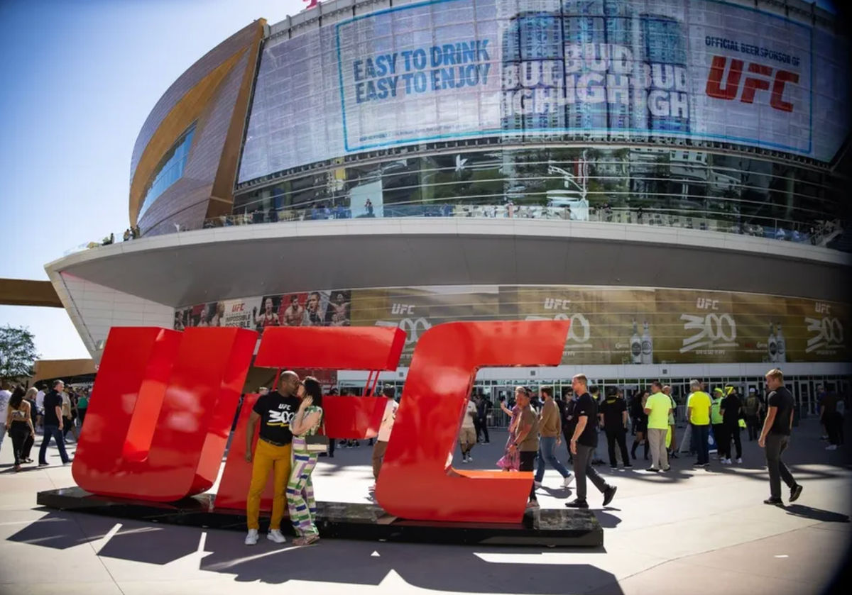 13 de abril de 2024; Las Vegas, Nevada, EUA; Um casal se beija em frente ao logotipo do UFC antes do UFC 300 na T-Mobile Arena. Crédito obrigatório: Mark J. Rebilas-Imagn Images