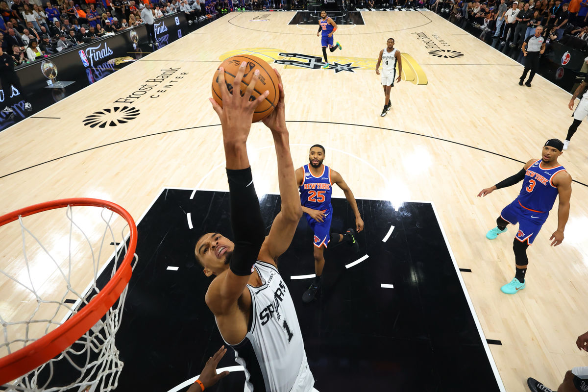 Jun 13, 2026; San Antonio, Texas, USA; San Antonio Spurs forward Victor Wembanyama (1) attempts a reverse dunk as New York Knicks guard Mikal Bridges (25) looks on at Frost Bank Center. Mandatory Credit: Geoff Burke-Imagn Images