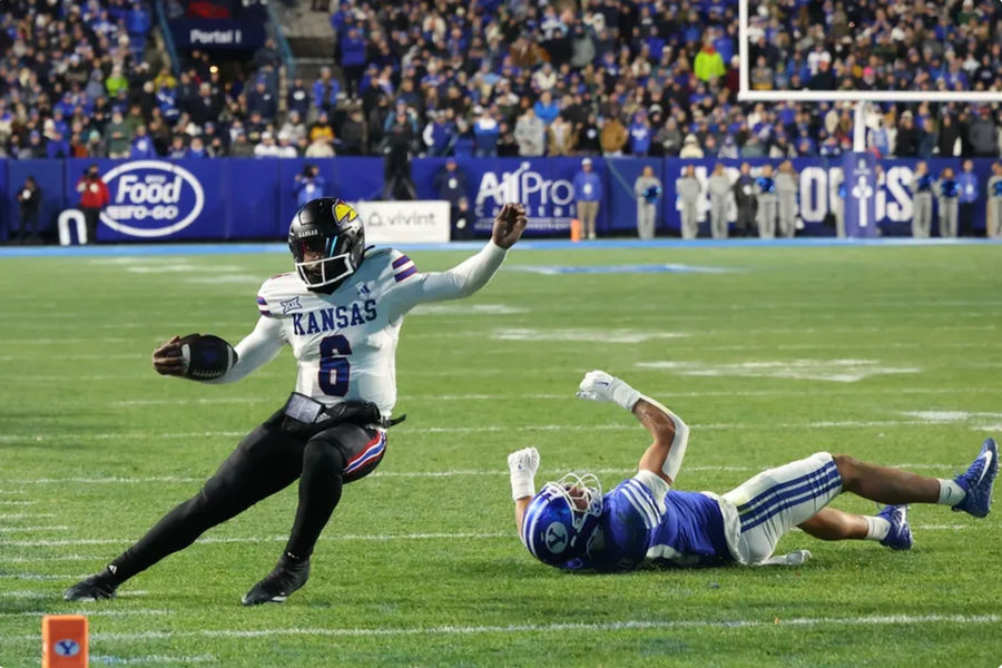 Nov 16, 2024; Provo, Utah, USA; Kansas Jayhawks quarterback Jalon Daniels (6) is tripped up by Brigham Young Cougars linebacker Jack Kelly (17) during the second quarter at LaVell Edwards Stadium. Mandatory Credit: Rob Gray-Imagn Images