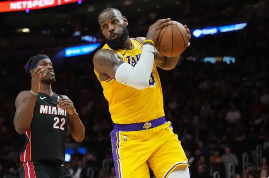 Dec 4, 2024; Miami, Florida, USA; Los Angeles Lakers forward LeBron James (23) grabs a rebound in front of Miami Heat forward Jimmy Butler (22) in the first half at Kaseya Center. Mandatory Credit: Jim Rassol-Imagn Images