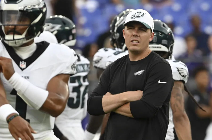 Aug 9, 2024; Baltimore, Maryland, USA; Philadelphia Eagles offensive coordinator Kellen Moore looks on as quarterback Jalen Hurts (1) throws before a preseason game against the Baltimore Ravens at M&T Bank Stadium. Mandatory Credit: Tommy Gilligan-Imagn Images