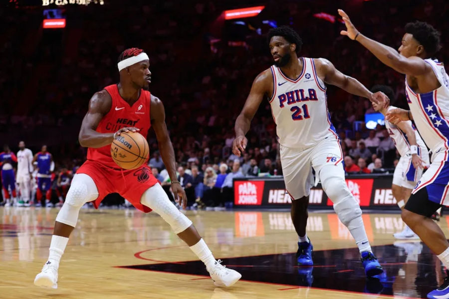 Nov 18, 2024; Miami, Florida, USA; Miami Heat forward Jimmy Butler (22) drives to the basket against Philadelphia 76ers center Joel Embiid (21) and guard Kyle Lowry (7) during the second quarter at Kaseya Center. Mandatory Credit: Sam Navarro-Imagn Images