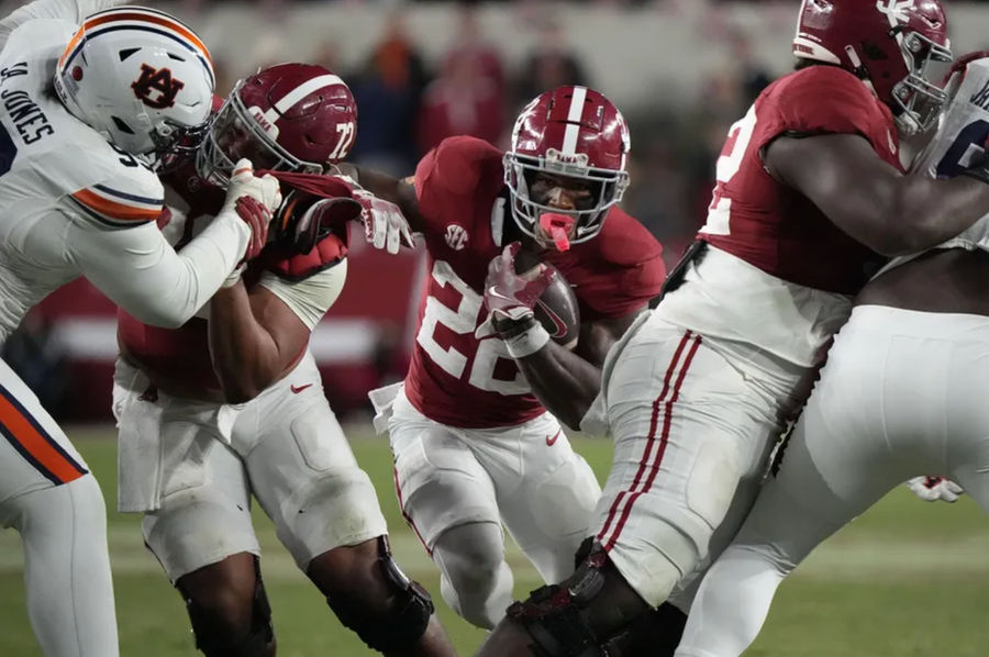 Nov 30, 2024; Tuscaloosa, Alabama, USA; Alabama Crimson Tide running back Justice Haynes (22) runs behind offensive lineman Parker Brailsford (72) and offensive lineman Tyler Booker (52) against the Auburn Tigers during the second half at Bryant-Denny Stadium. Alabama won 28-14. Mandatory Credit: Gary Cosby Jr.-Imagn Images