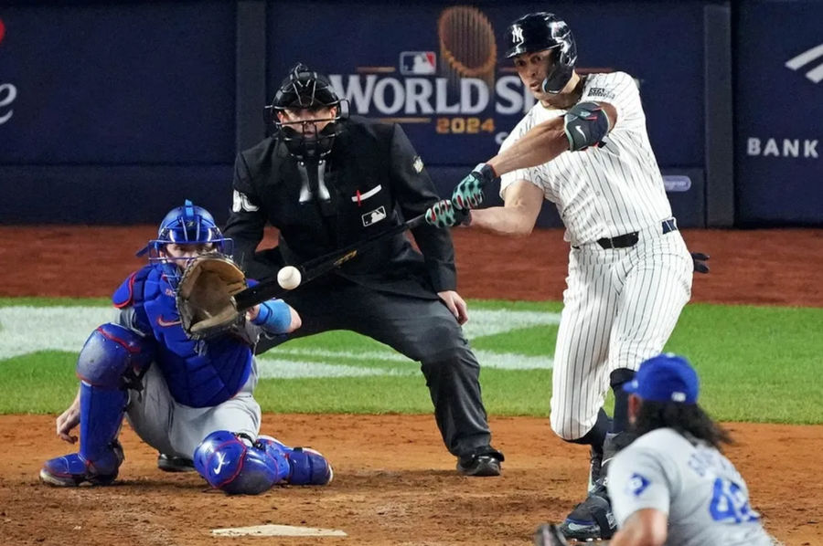 Oct 30, 2024; New York, New York, USA; New York Yankees designated hitter Giancarlo Stanton (27) hits an RBI sacrifice fly during the sixth inning against the Los Angeles Dodgers in game four of the 2024 MLB World Series at Yankee Stadium. Mandatory Credit: Robert Deutsch-Imagn Images