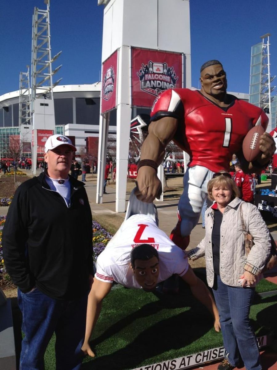 Colin Kaepernick&#39;s Parents Posed In Front Of A Statue Depicting The Atlanta Falcons Giving Their Son A Wedgie