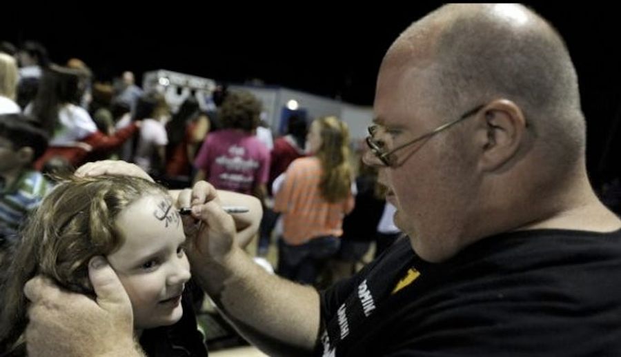 Presenting A Picture Of Chad McGhee Signing A Young Knox City Greyhounds Fan's Forehead